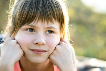 Portrait of pretty child girl with gray eyes and long fair hair leaning on her hands smiling...