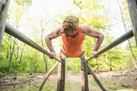 Mature man doing push-ups on parallel bars at park