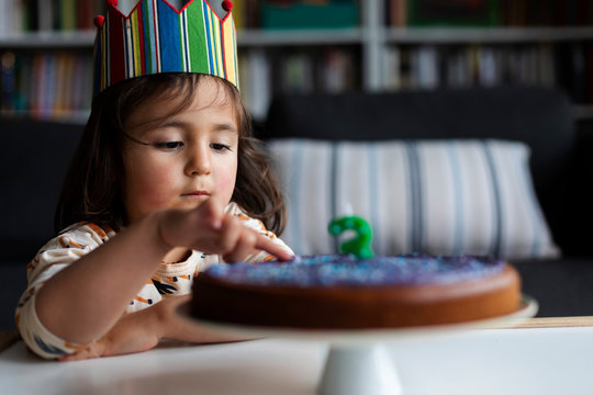 Portrait of little girl touching birthday cake