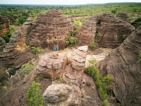 Burkina Faso, Man with arms outstretched on top of rock at Domes of Fabedougou