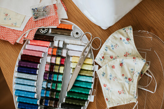 Close-up of floral face masks with sewing items on table at home during COVID-19