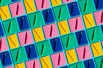Pattern of colorful notebooks and matching felt tip pens