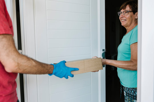 Smiling senior woman receiving package from delivery person at doorway