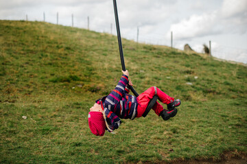 Cute child blond girl rides on play equipment in a children's playground.