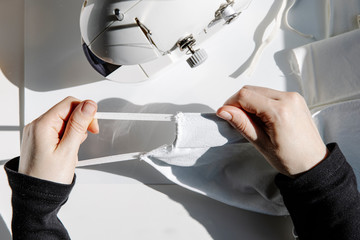 From top anonymous seamstress sitting at table checking freshly made face masks in workshop