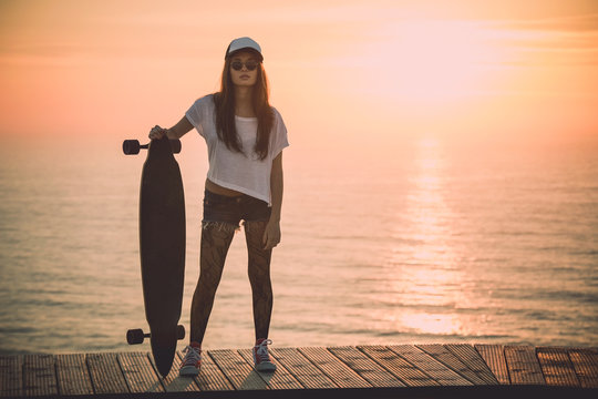 Beautiful and fashion young woman posing with a skateboard