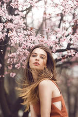 Fashion portrait of a young woman in front of the cherry blossom tree