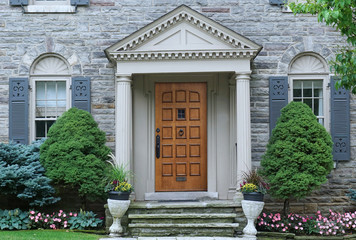 Fototapeta na wymiar Portico front door entrance of older stone faced house with shutters around the windows