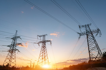 Fototapeta premium High-voltage power lines at sunset or sunrise. High voltage electric transmission tower