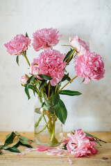 Vertical picture of bouquet of pink peonies in glass jar on on white background. Spring summer floral background with peonies.