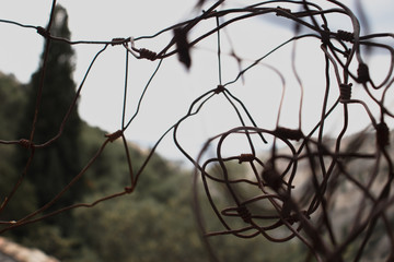 Closeup of a rusty tangled fence , dark cloudy day and dark mood. Concept of prisoners and lack of freedom