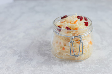 Homemade sauerkraut with cranberries in a glass jar on a gray background. Preparations for the winter. Fermented food. The best prebiotic. Place for text