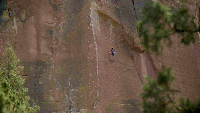 Climber sport climbing recreation high on orange desert wall cliff using chalk in smith rock state park central oregon pacific northwest usa