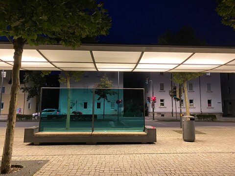 Nachtszene Haltestelle moderne Beleuchtung Windfang Glas gr&uuml;n dahinter Ampel rot