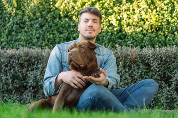 Caucasian young man and his dogmposing sitting on the garden