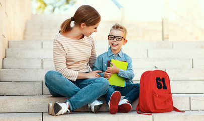 first day at school. mother and little schoolboy son sit on the stairs together.