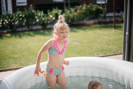 blonde girl having fun in a small pool on a hot summer day