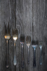 Various vintage patina forks on a wooden background. Photo in grunge style, vintage