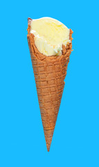 side view vanilla flaovr ice cream cone with couple of bites on a blue background
