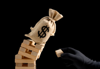 hand with black glove damaging the foundation of an US money bag and made it fell down