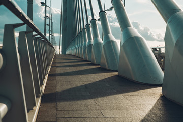 An empty walk path on a modern steel and white concrete bridge.