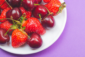 Cherries and strawberries on the white plate