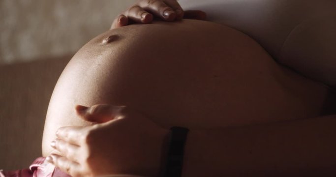 Pregnant girl stroking naked belly