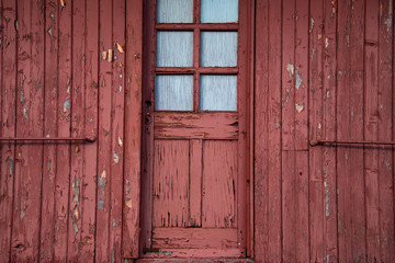 Obraz na płótnie Canvas Old red wooden door with peeling paint