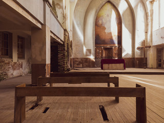 Benches and altar inside an abandoned church. ancient interior of religious building. cross stands...