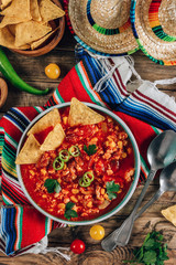 Chili Con Carne in bowl with tortilla chips on wooden background. Mexican cuisine.