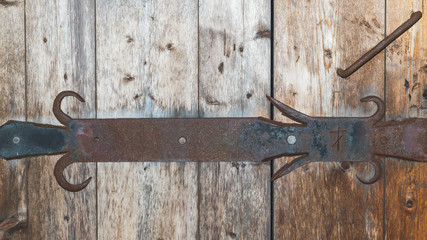 Detail of forged iron latch of wooden door. old handwork forging. scratched symbol of religious...