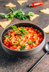 Chili Con Carne in bowl with tortilla chips on dark background. Mexican cuisine.
