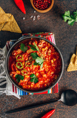 Chili Con Carne in bowl with tortilla chips on dark background. Mexican cuisine.