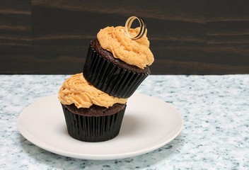 Two chocolate cupcakes with peanut butter icing with one on top of the other.  Copy space.