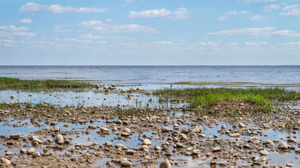 Shore of the sea. seascape with horizon line. sky with clouds. silt coast with pebbles