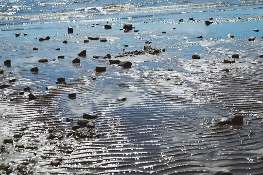 Stones on wavy wet sand. pebbles on the seashore. abstract background