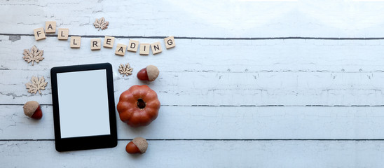 Fall reading:  top view of an empty ebook on a rustic white wood surface surrounded by fall-themed items and wooden letter tiles.
autumn themed ereader flat lay with copy space   