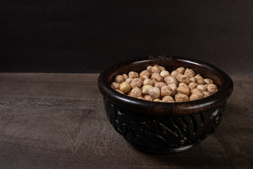 Dark wood casserole with uncooked chickpeas on a wooden board