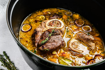 Cast iron pan with ossobuco made of cross cut veal shank. ossobuco meat stew. Gray background. Top view