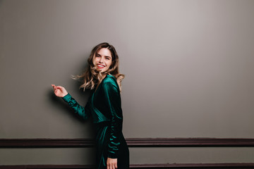 Wonderful girl in green velvet dress enjoying photoshoot. Enthusiastic young woman with wavy brown...