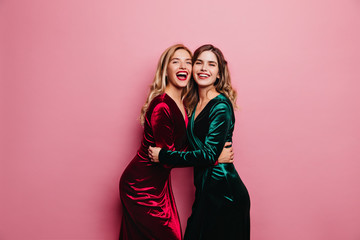 Romantic woman in green dress embracing her sister. Happy caucasian girls in velvet outfit laughing...