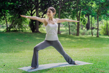 Healthy women doing yoga in the moring at the park . concept healthy and outdoor activity. Warrior2 pose