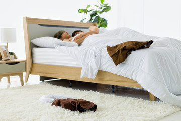 Homosexual gay couples lying on white bed.