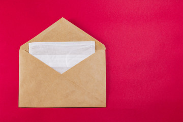 Medical face mask in a grey envelope on a red background, close-up.