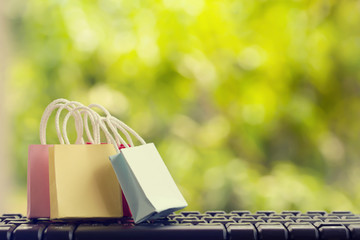 E-Commerce concept. : Color paper shopping bags with on notebook keyboard in the natural green...