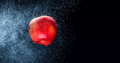 Fresh  Variegated apple  gets sprayed with water on black background. Concept of summer, health and fun. Copy Space