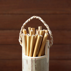 bamboo straw in bamboo cylinder on wood background with copy space ( straw from natural material / green product concept )
