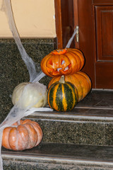 Spooky Halloween pumpkin jack-o-lanterns with spider web on the steps at a door. Decorations for Halloween holiday