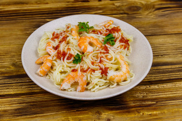Spaghetti pasta with prawns, tomato sauce and parsley on wooden table
