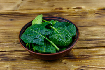 Fresh green spinach leaves in bowl on a wooden table